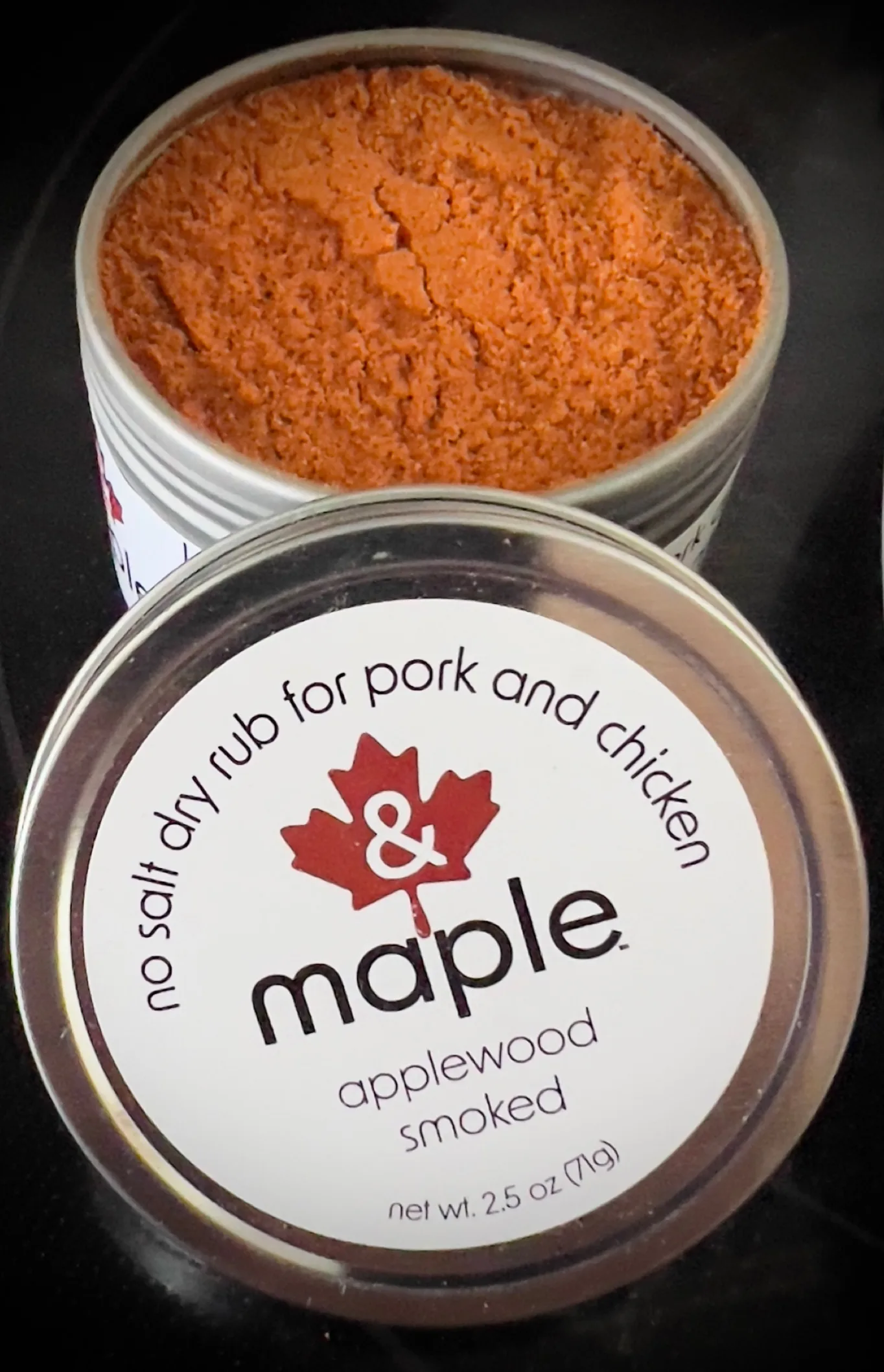 Open tin of & Maple Applewood Smoked seasoning beside its labeled lid.